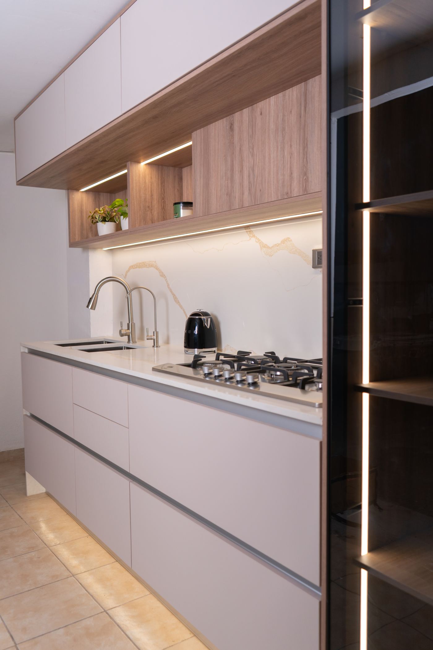 Cocina con cubierta blanca, gabinetes claros, detalles en madera e iluminación integrada