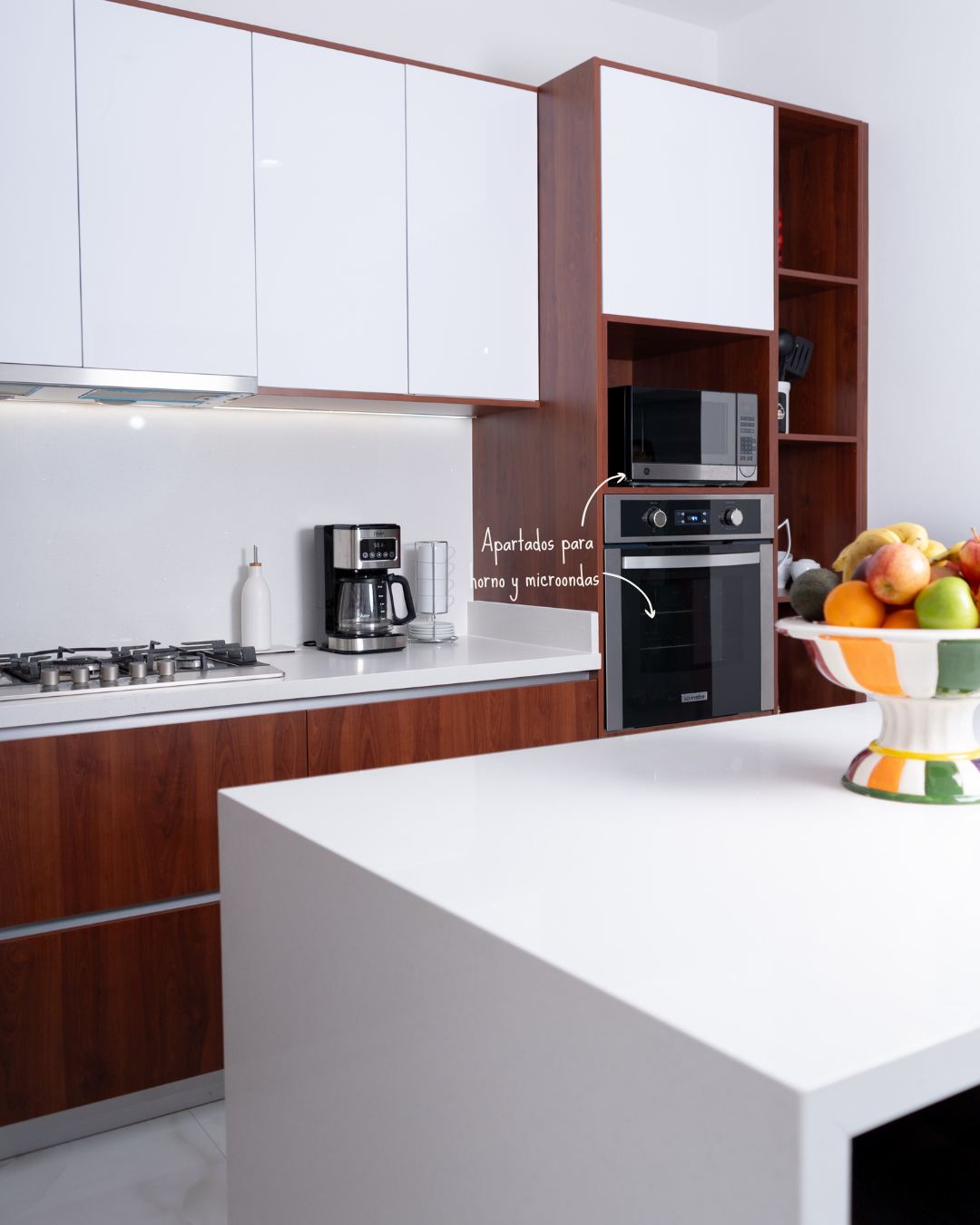 Cocina con isla blanca de cascada y gabinetes de madera oscura